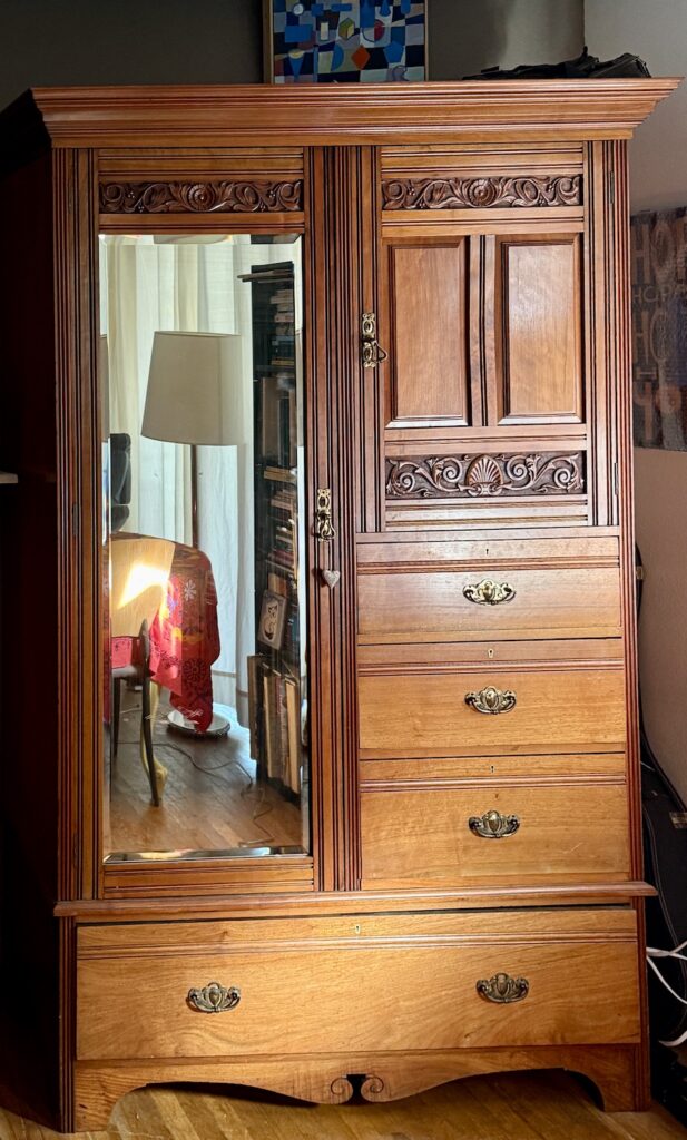 A wardrobe closet or armoire for holding clothing. 
